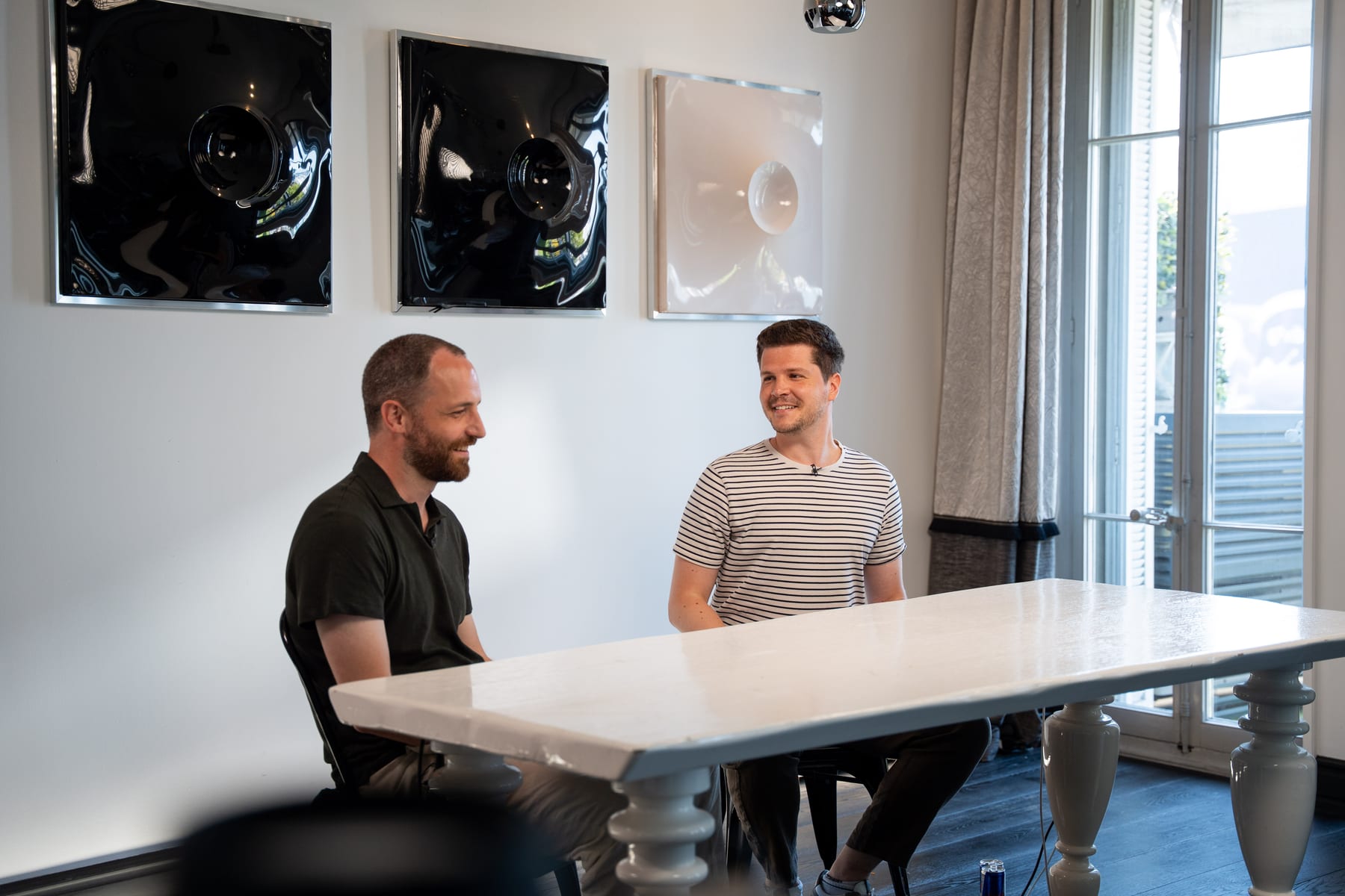 Maarten Claes and Dieter De Mesmaeker face each other across a white table on the Conveo podcast set at Cannes Lions 2026.