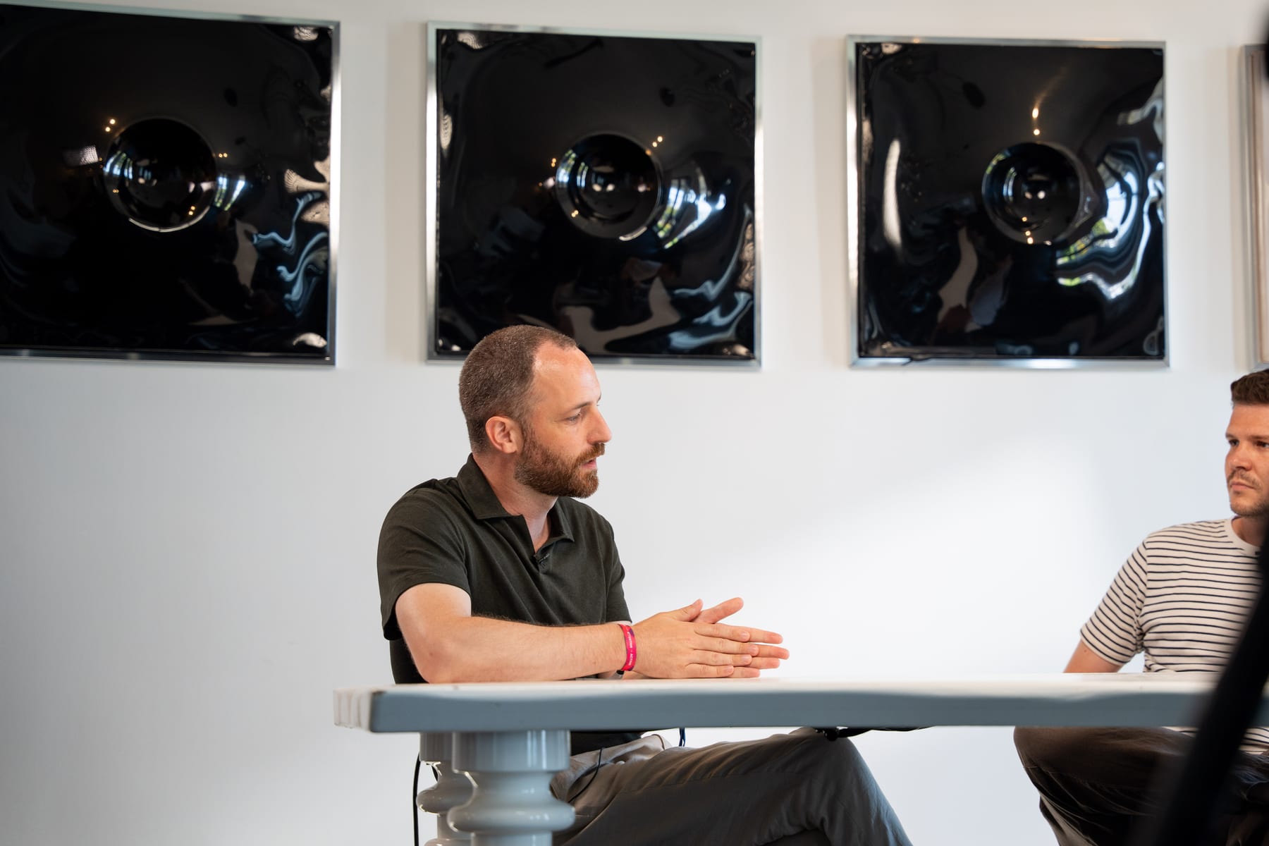 Maarten Claes speaks with his hands folded on the table, with Dieter De Mesmaeker at the edge of the frame, at Cannes Lions 2026.