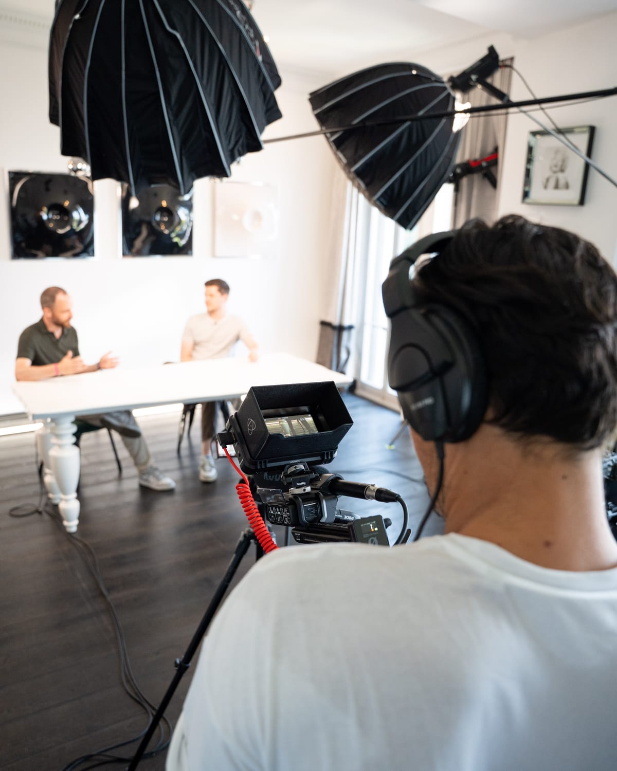 A camera operator in headphones films Maarten Claes and Dieter De Mesmaeker from behind the rig at Cannes Lions 2026.