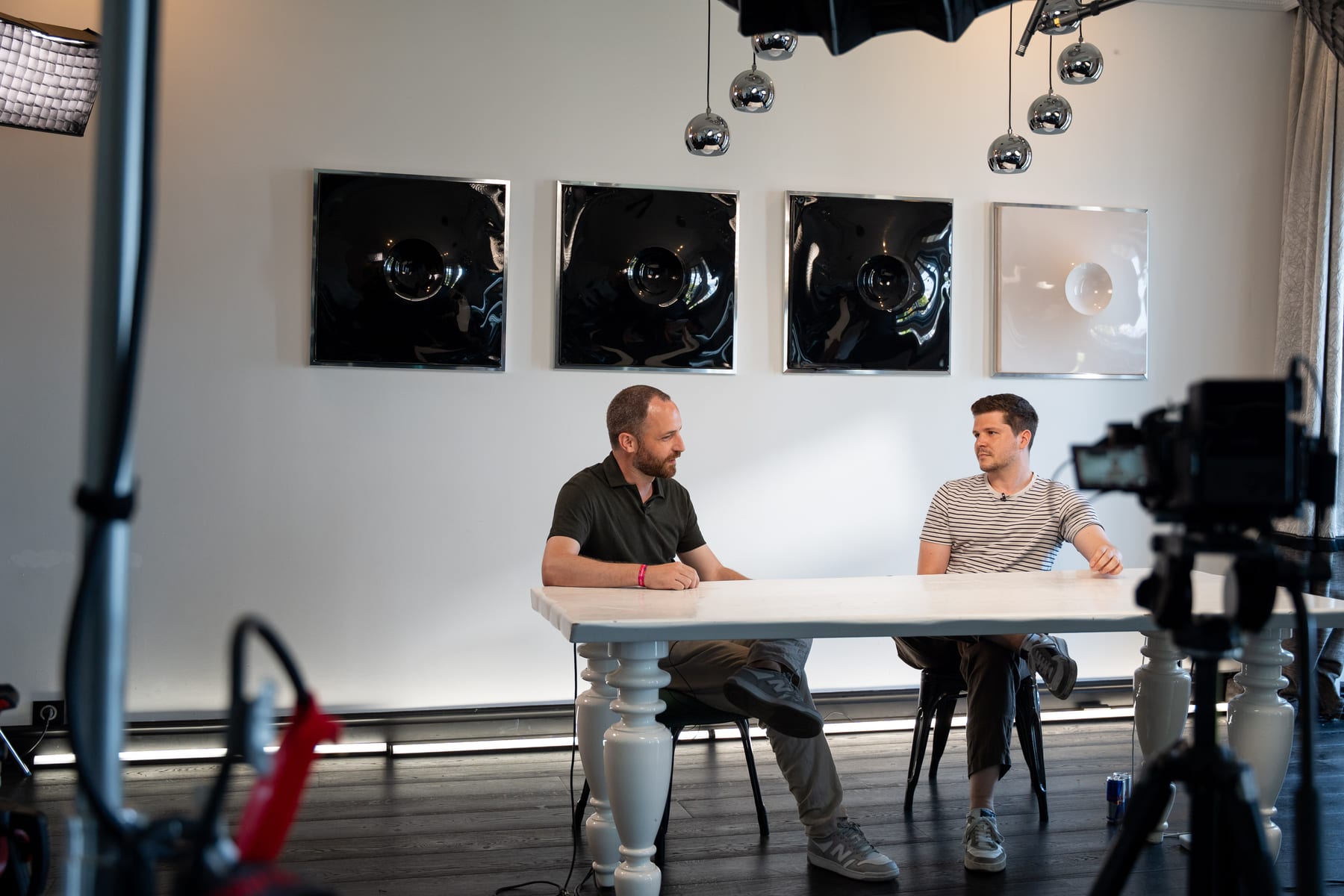 Wide view of the Conveo podcast set with studio lights, black wall art and Claes and De Mesmaeker at the white table at Cannes Lions 2026.