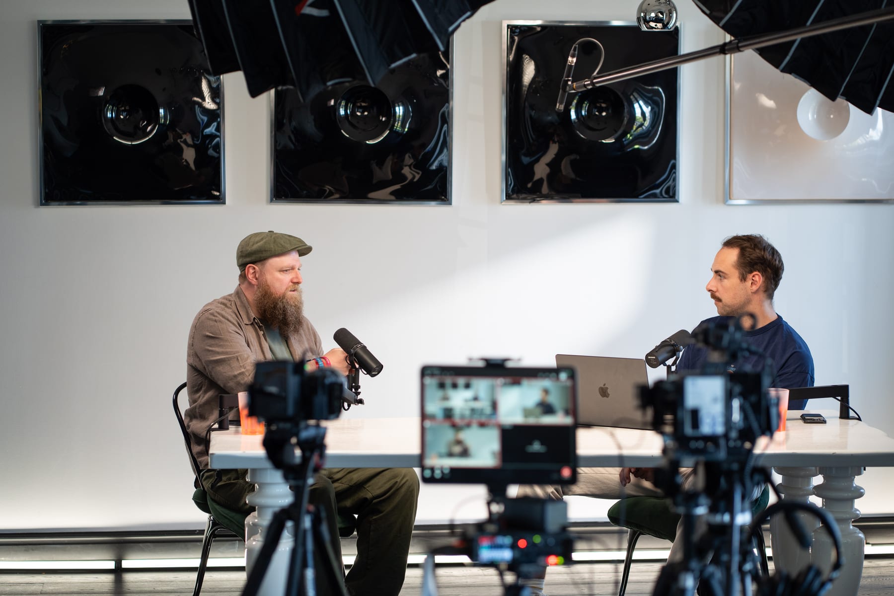Wesley ter Haar talks with his hand raised while the host faces him across the podcast table, with cameras and a monitor in the foreground at Cannes Lions 2026