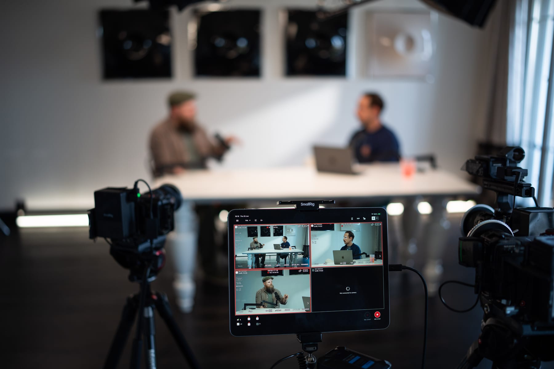 A tablet monitor shows four camera feeds of the recording while Wesley ter Haar and the host sit out of focus at the table behind it at Cannes Lions 2026
