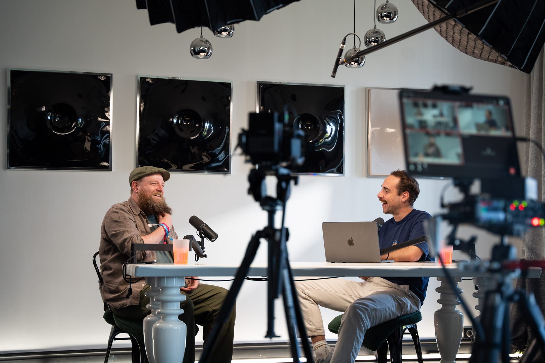 Wesley ter Haar and the host laugh together at the podcast table, seen past a camera tripod and monitor at Cannes Lions 2026