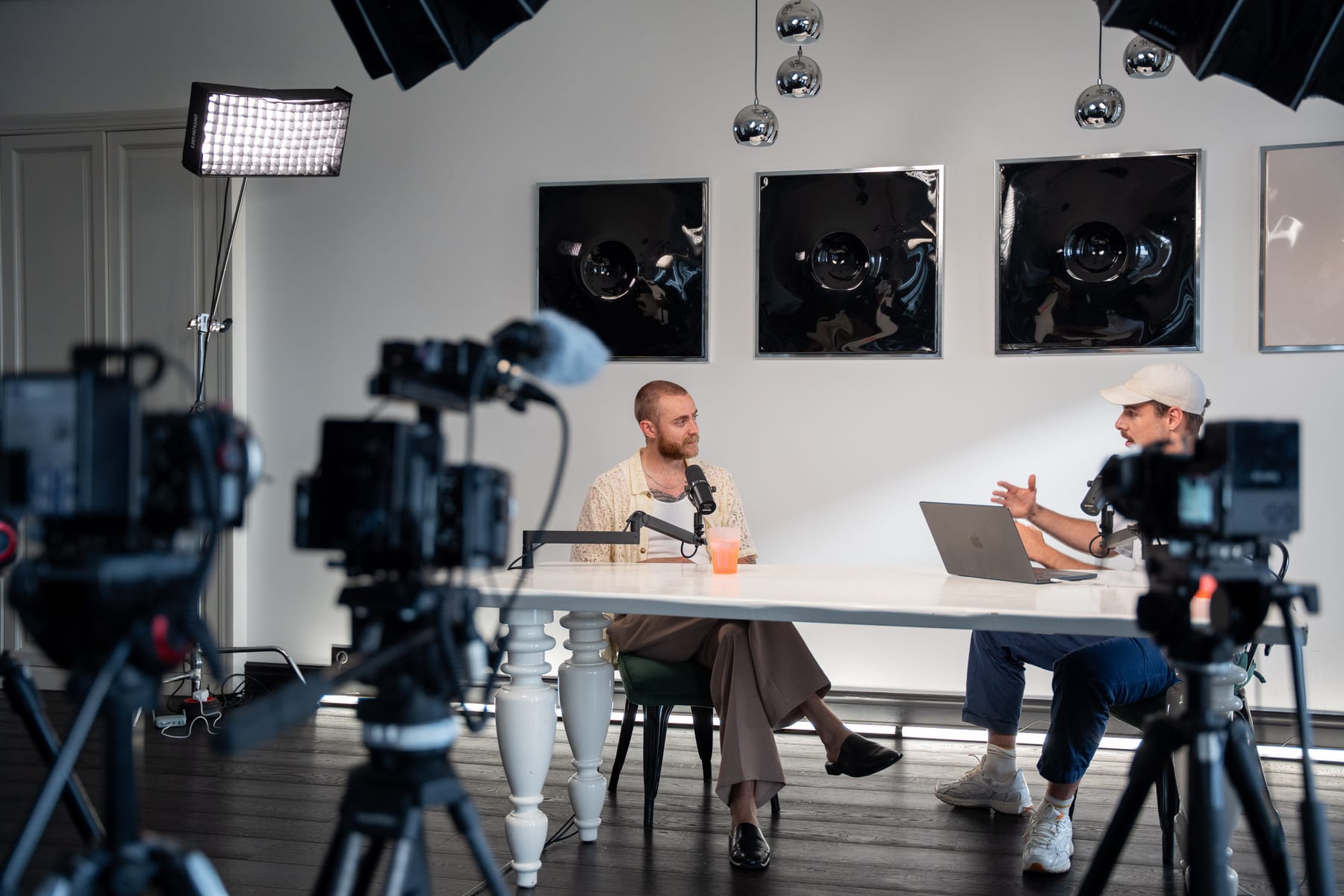 Camera operators film Brock Johnson and the host at a white table on the Conveo podcast set at Cannes Lions 2026.