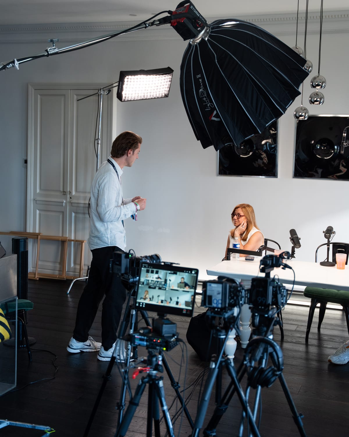 Carole Irgang seated at the podcast table as a crew member stands among the cameras, softbox and monitors of the Conveo set at Cannes Lions 2026.