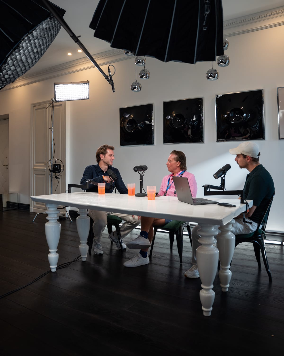 Wide view of the Conveo podcast set, with Christopher Nurko and two hosts at a white table beneath large softbox lights at Cannes Lions 2026.