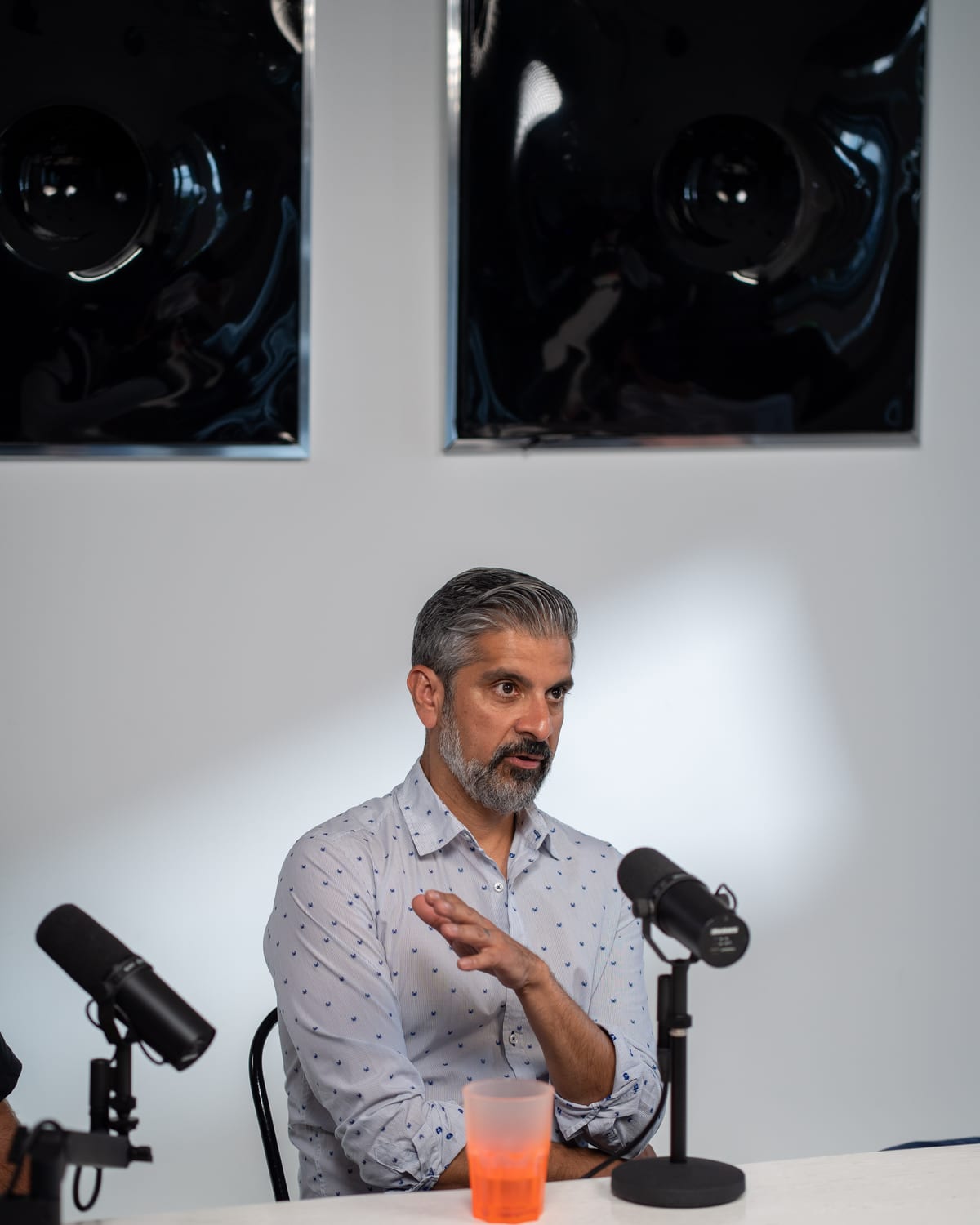 Saneel Radia speaks into a microphone at the podcast table on the Conveo set at Cannes Lions 2026.