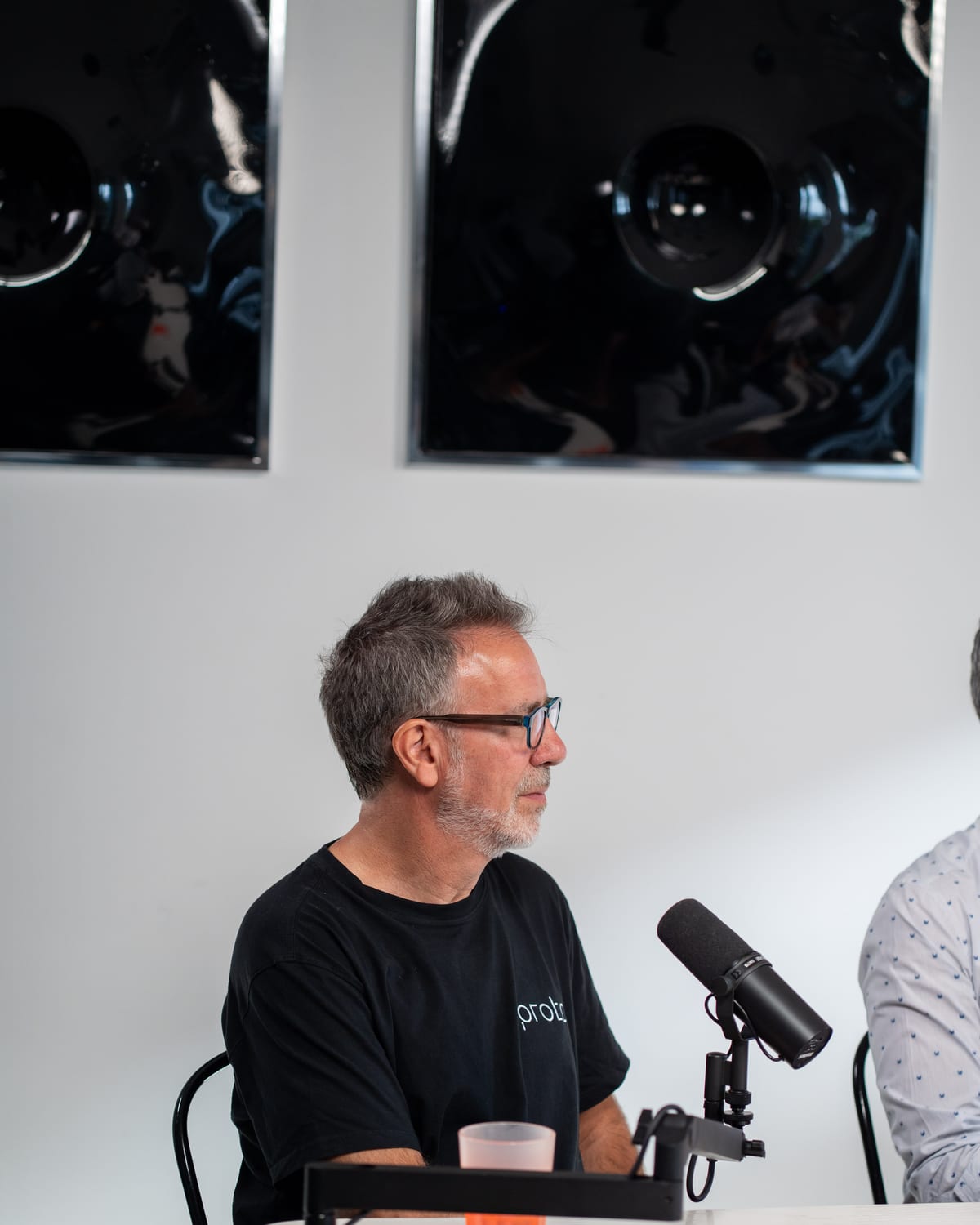 Barry Wacksman, in a black Proto T-shirt and glasses, talks at the microphone on the Conveo podcast set at Cannes Lions 2026.