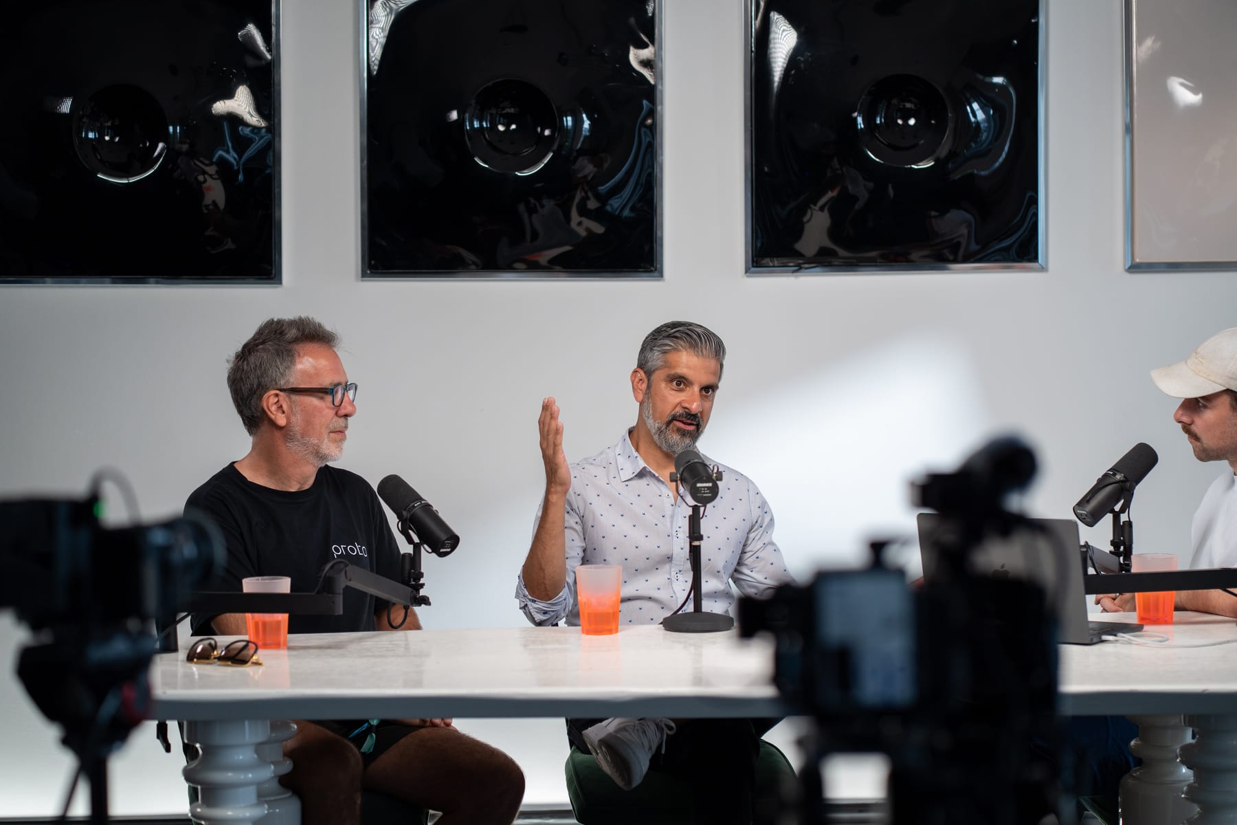 Saneel Radia gestures as he makes a point while Barry Wacksman looks on at the podcast table at Cannes Lions 2026.