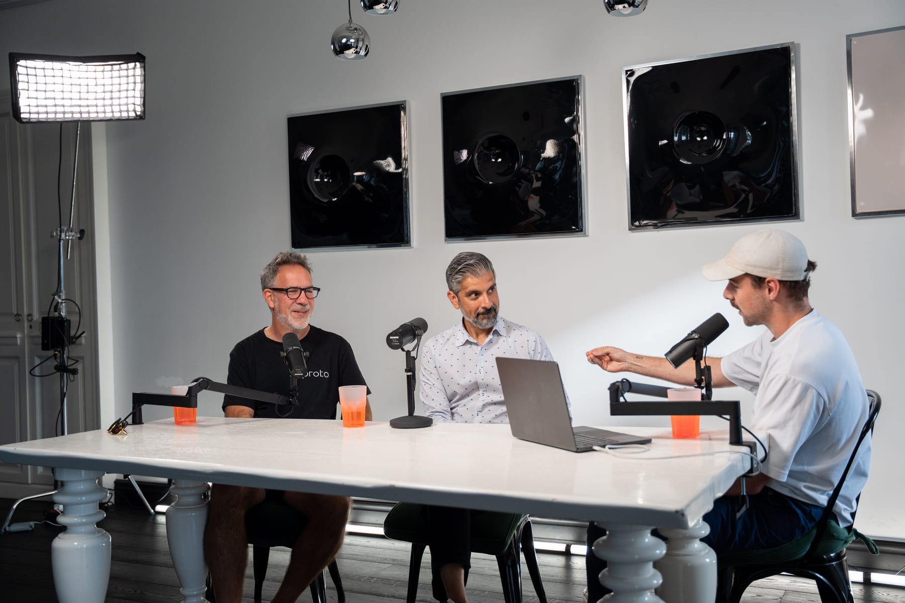 Barry Wacksman and Saneel Radia face the host across a white table with microphones and laptops on the Conveo podcast set at Cannes Lions 2026.