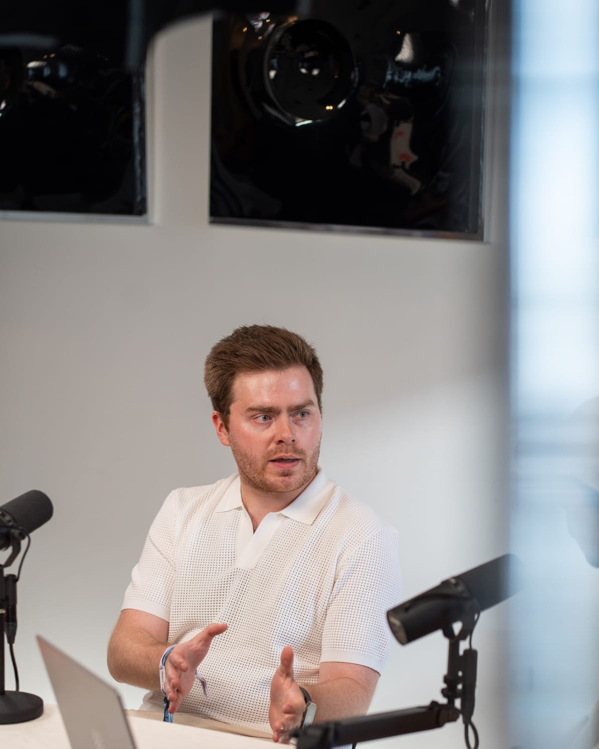 Doug Tallmadge of Gradial in a white polo gesturing with both hands as he makes a point at the podcast table at Cannes Lions 2026