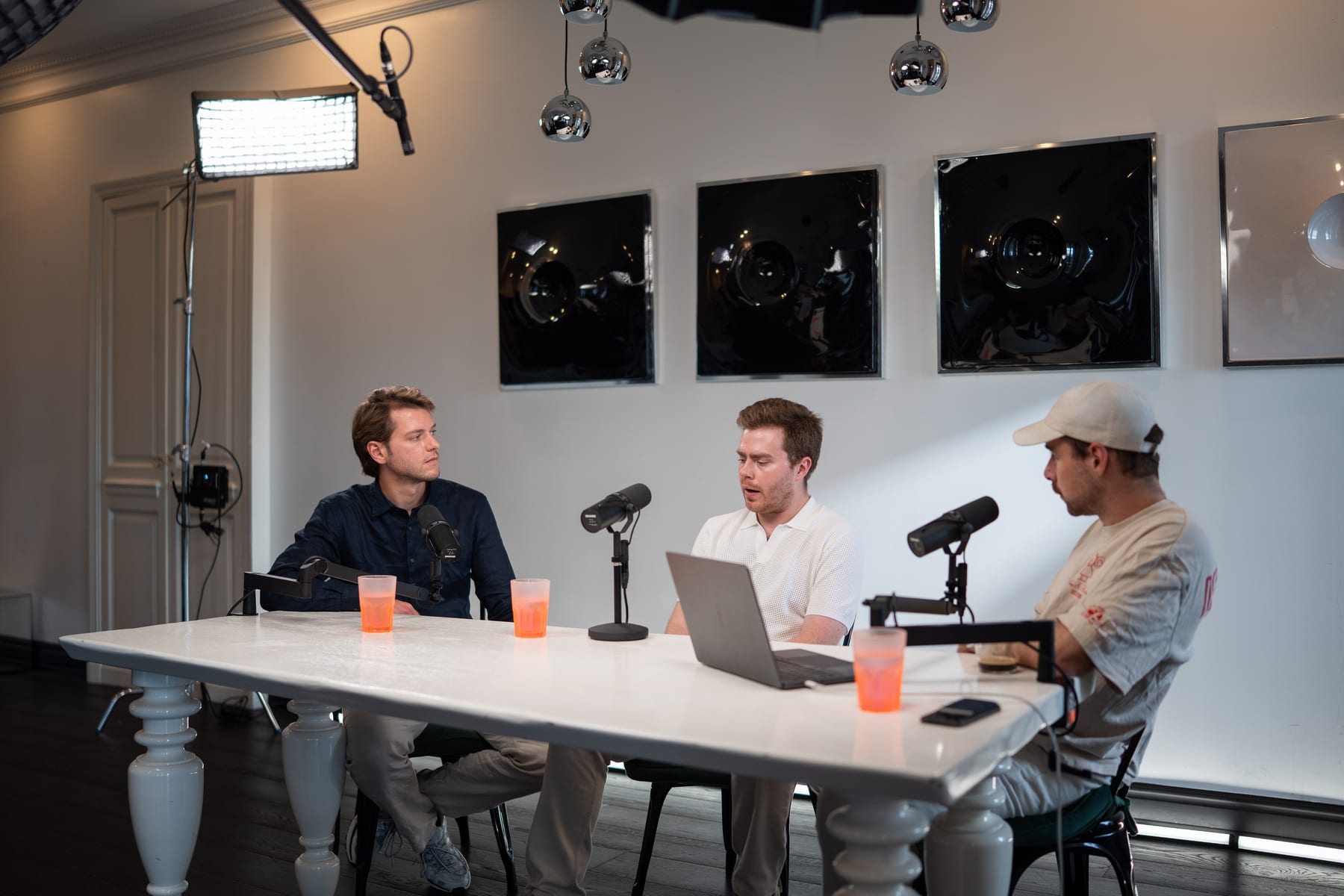 Hendrik Van Hove, Doug Tallmadge and a third person in a cap talking around a white table with microphones and laptops at Cannes Lions 2026