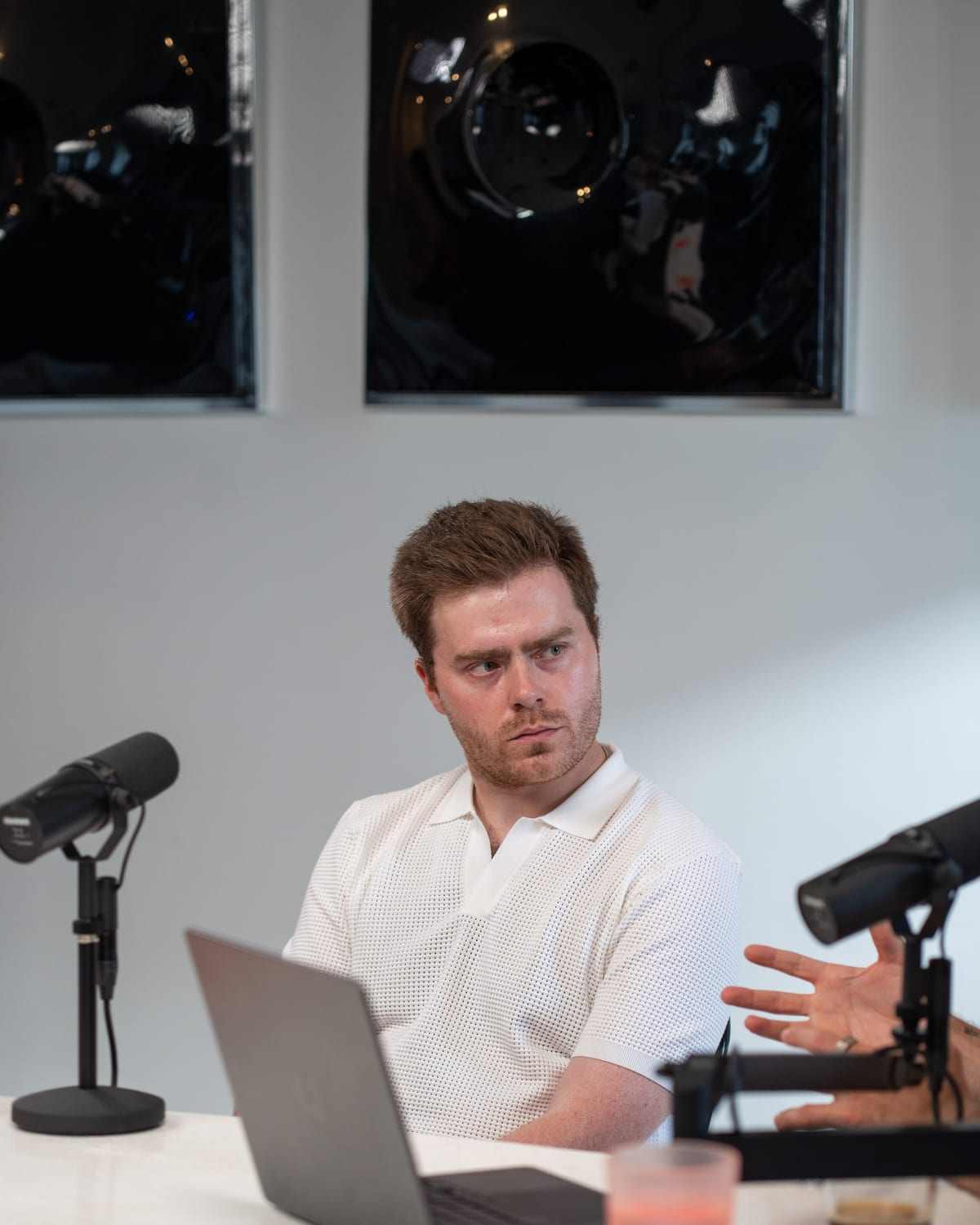 Doug Tallmadge turning toward the host mid-conversation, a laptop and microphone in front of him, on the Conveo podcast set at Cannes Lions 2026