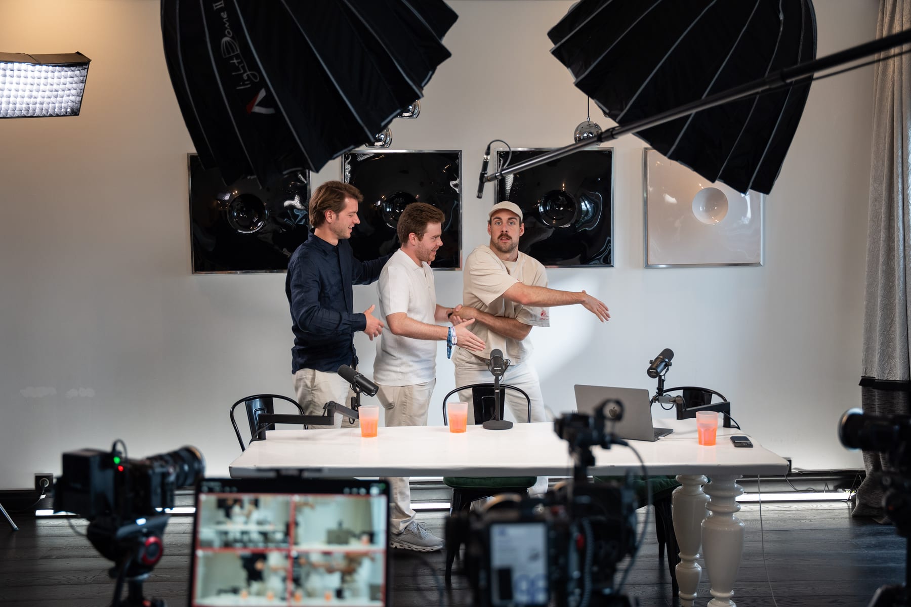 Hendrik Van Hove, Doug Tallmadge and a third person sharing a laugh at the podcast table behind a row of cameras at Cannes Lions 2026