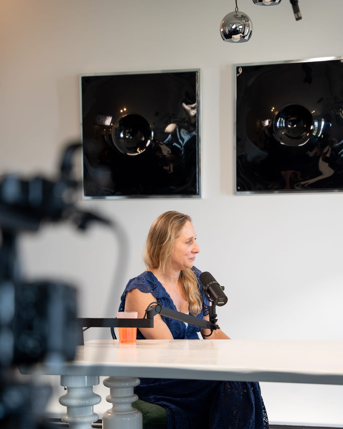 Karen Ehrlich seated at the podcast table in a blue dress, talking at the microphone, at Cannes Lions 2026