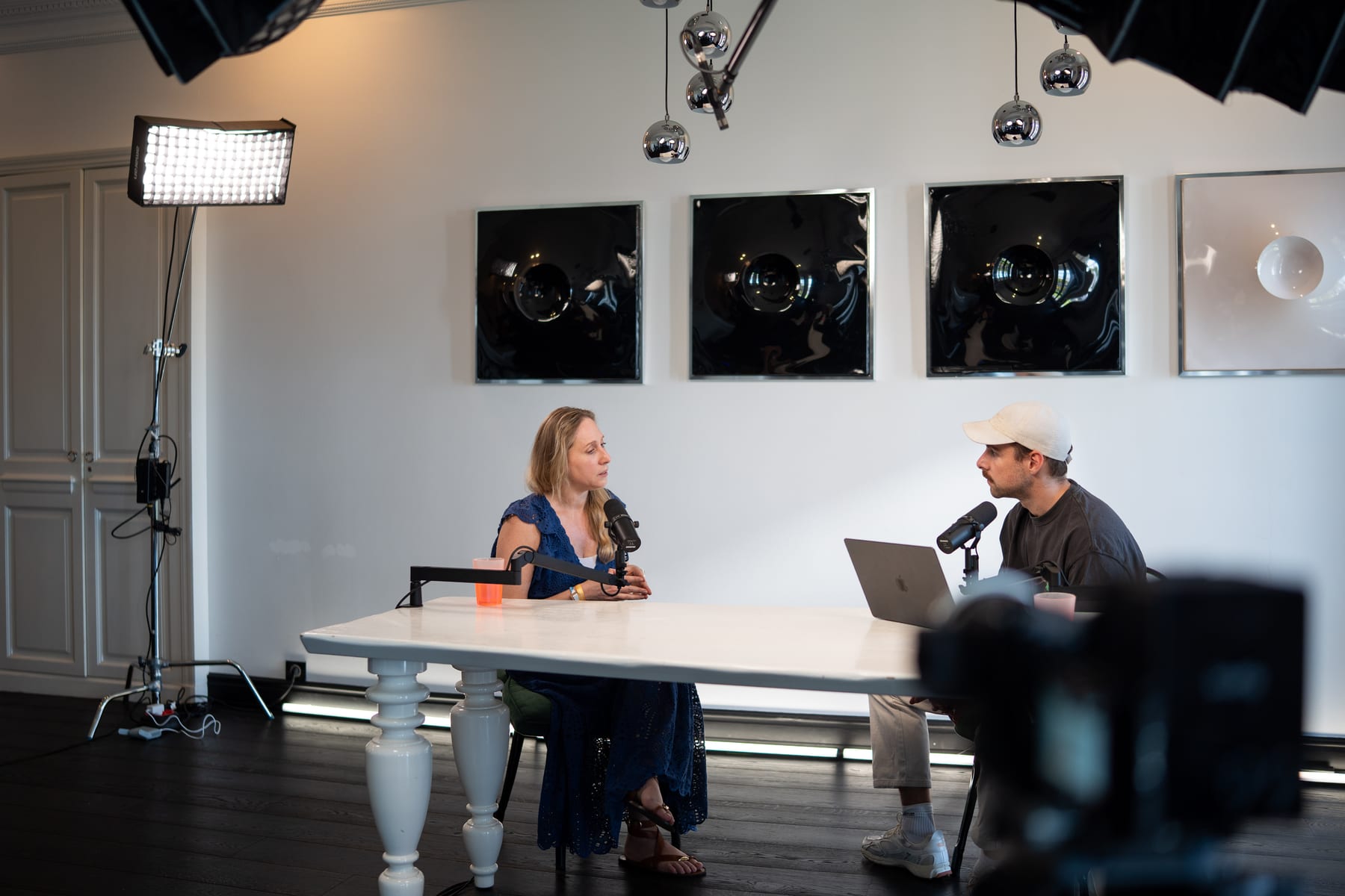 Karen Ehrlich and the host seated at opposite ends of the long white table in the bright Conveo podcast studio at Cannes Lions 2026
