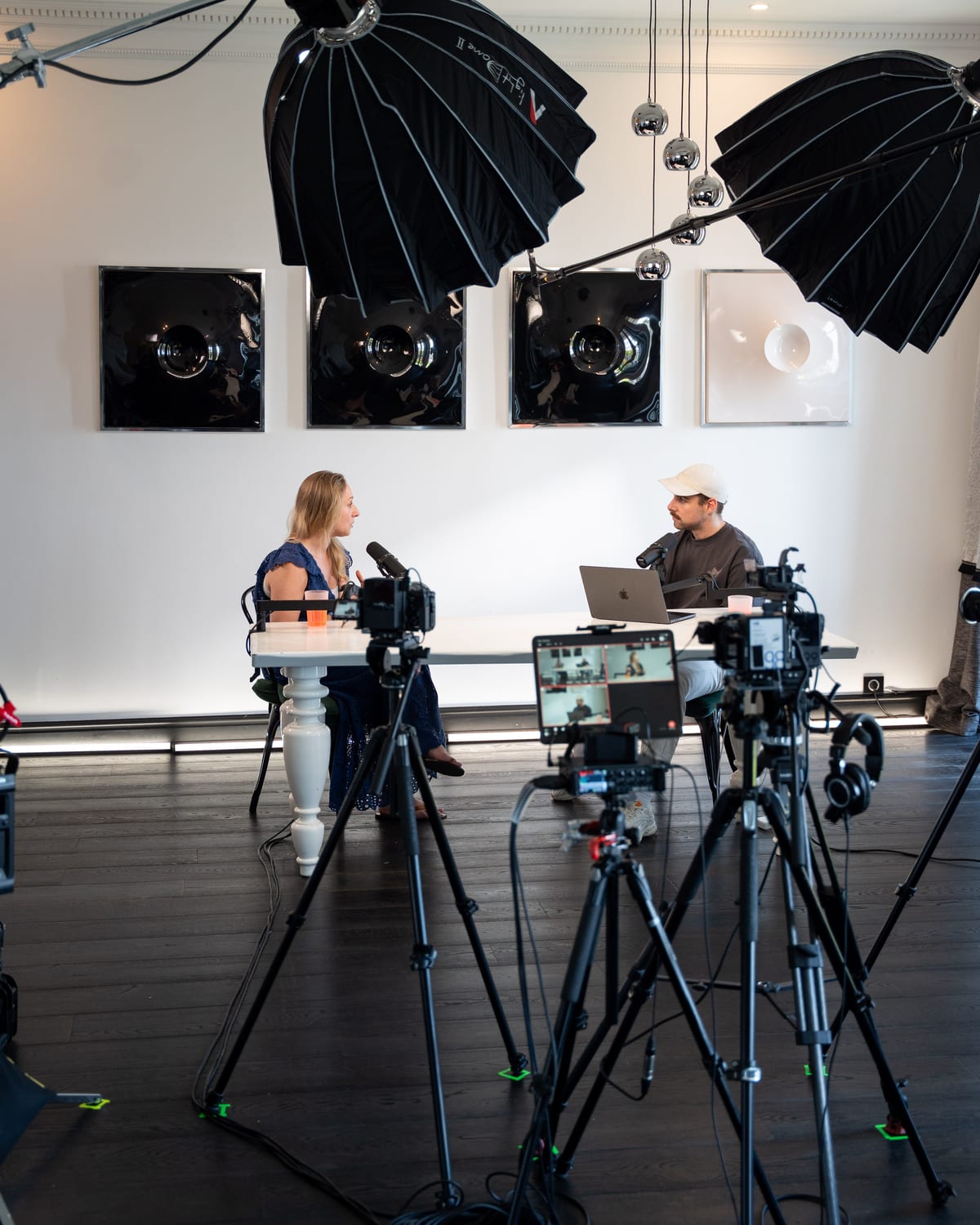 Vertical view of the podcast set with tall softbox lights and tripods framing Karen Ehrlich and the host at the table at Cannes Lions 2026