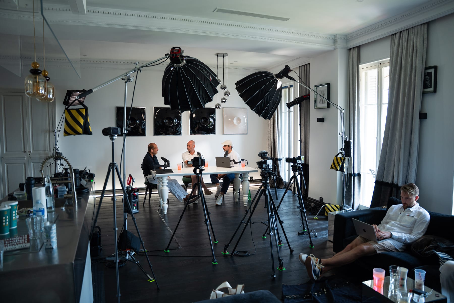Wide view of the Conveo podcast set, with softbox lights, camera tripods and a crew member on a sofa, as Kees Kruythoff, Niels Schillewaert and Tom Husson record at Cannes Lions 2026