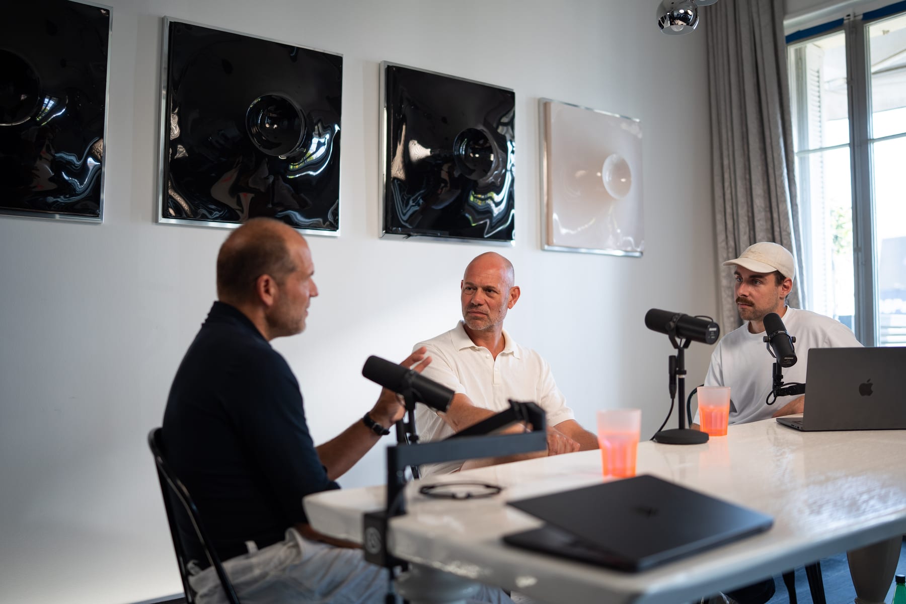 Kees Kruythoff gestures as he talks while Niels Schillewaert and host Tom Husson follow along at the podcast table at Cannes Lions 2026