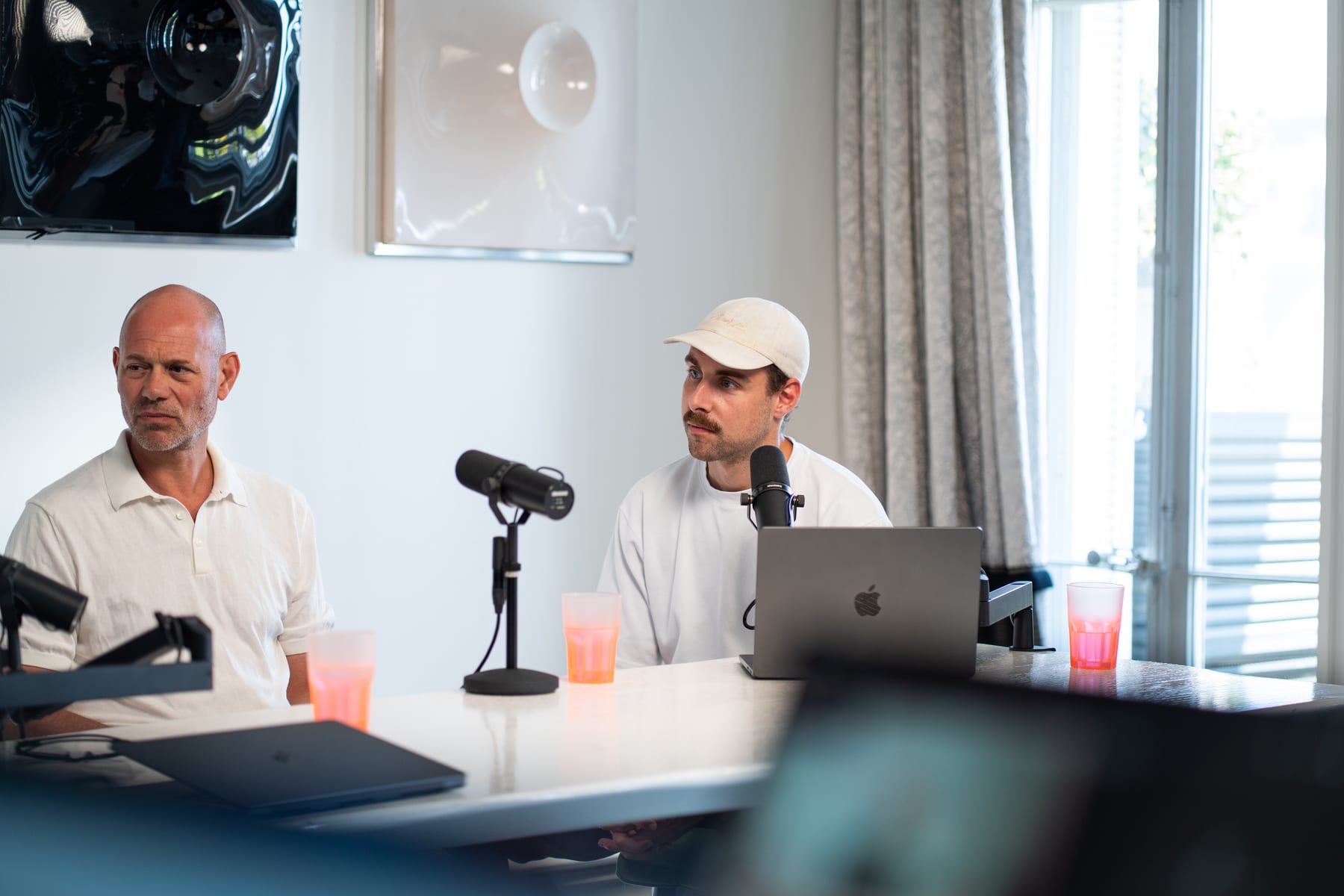 Niels Schillewaert and host Tom Husson seated at their microphones beside a tall window on the Conveo podcast set at Cannes Lions 2026
