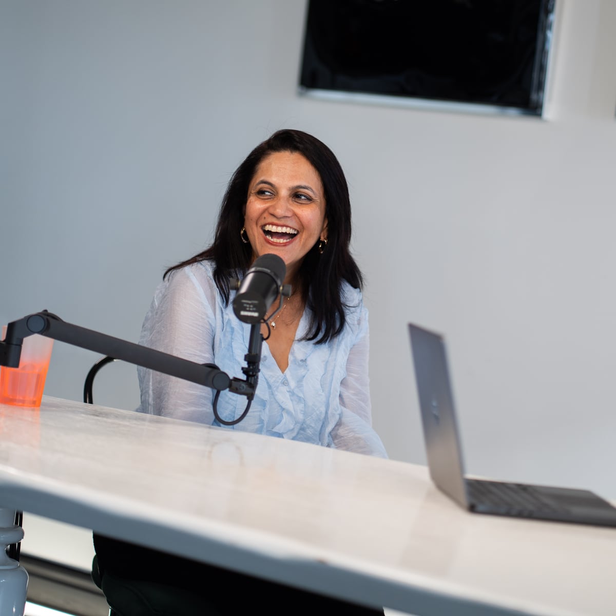 Lulu Raghavan of Landor laughing at the microphone on the Conveo podcast set at Cannes Lions 2026
