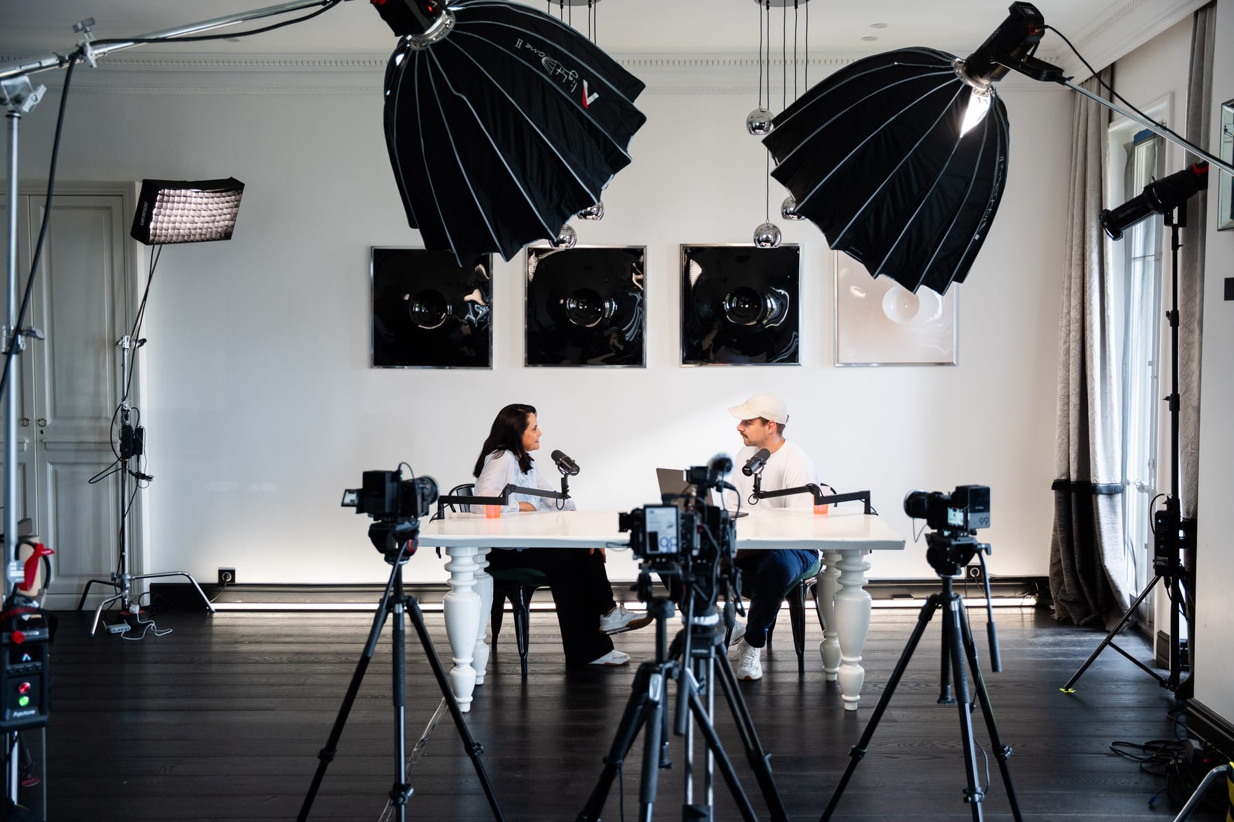 Wide view of the Conveo podcast studio with softbox lights, camera rigs and Lulu Raghavan seated across from the host at a white table at Cannes Lions 2026.
