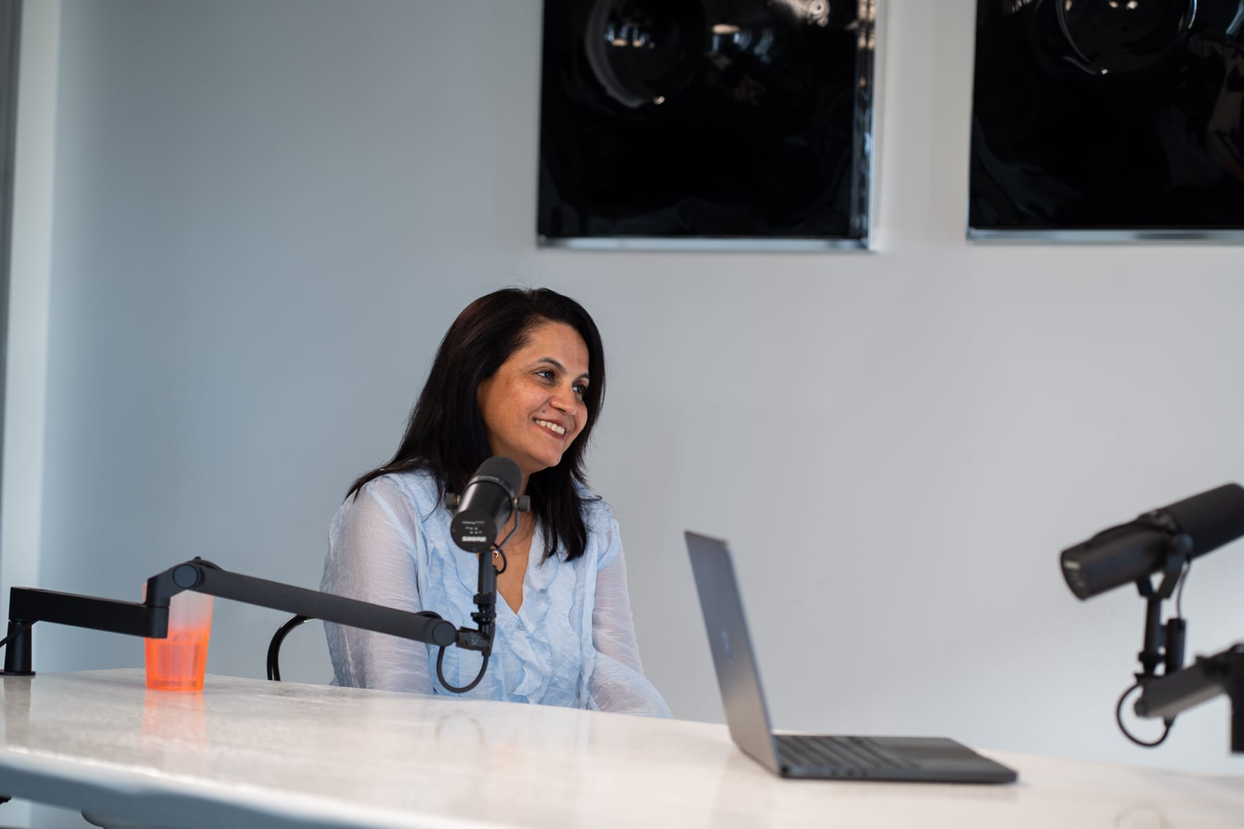 Lulu Raghavan of Landor smiling as she speaks into a microphone at the podcast table at Cannes Lions 2026.