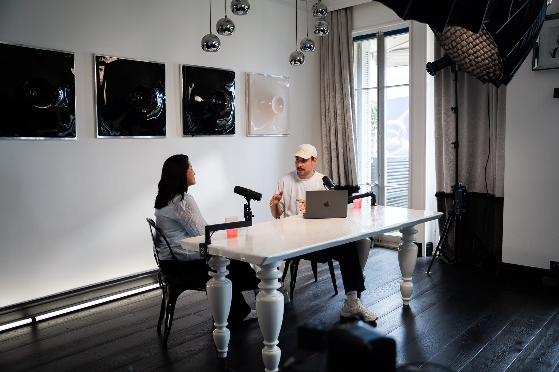 Side view of Lulu Raghavan and the host in conversation at the white podcast table in the studio at Cannes Lions 2026.