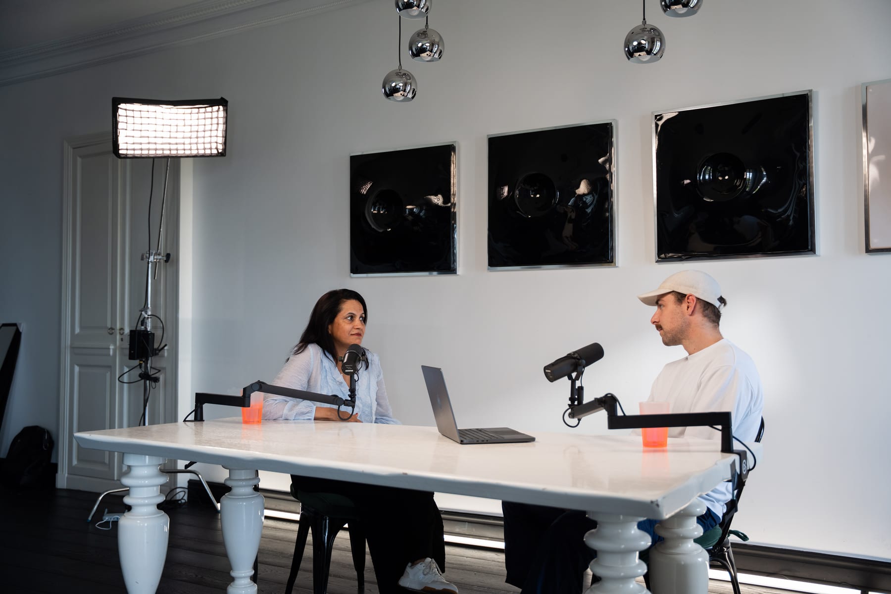 Lulu Raghavan and the host talk across the podcast table with microphones and a laptop at Cannes Lions 2026.