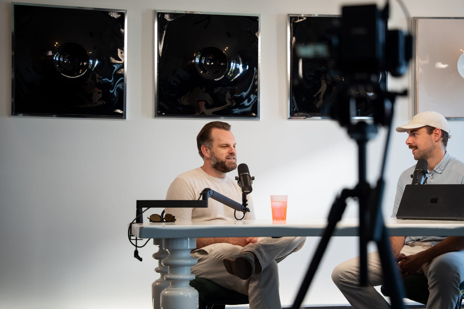 Matt Hammel of AirOps talks into a microphone while the host in a white cap faces him across the table, with a camera rig in the foreground at Cannes Lions 2026