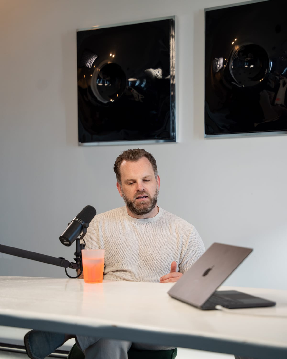 Matt Hammel gestures as he speaks at the podcast table, a microphone and laptop in front of him at Cannes Lions 2026