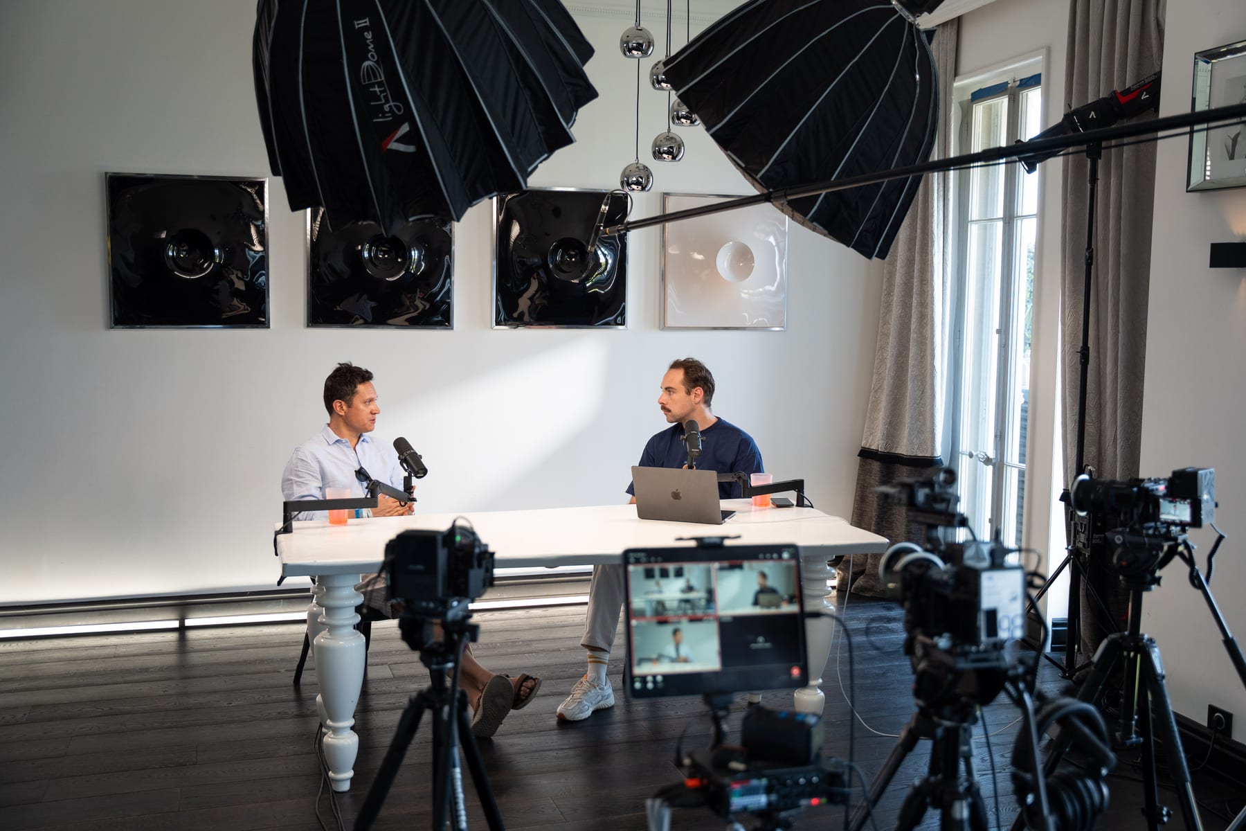 Miguel Avalos and the host talk across a white table at their microphones while cameras record the Conveo podcast at Cannes Lions 2026.