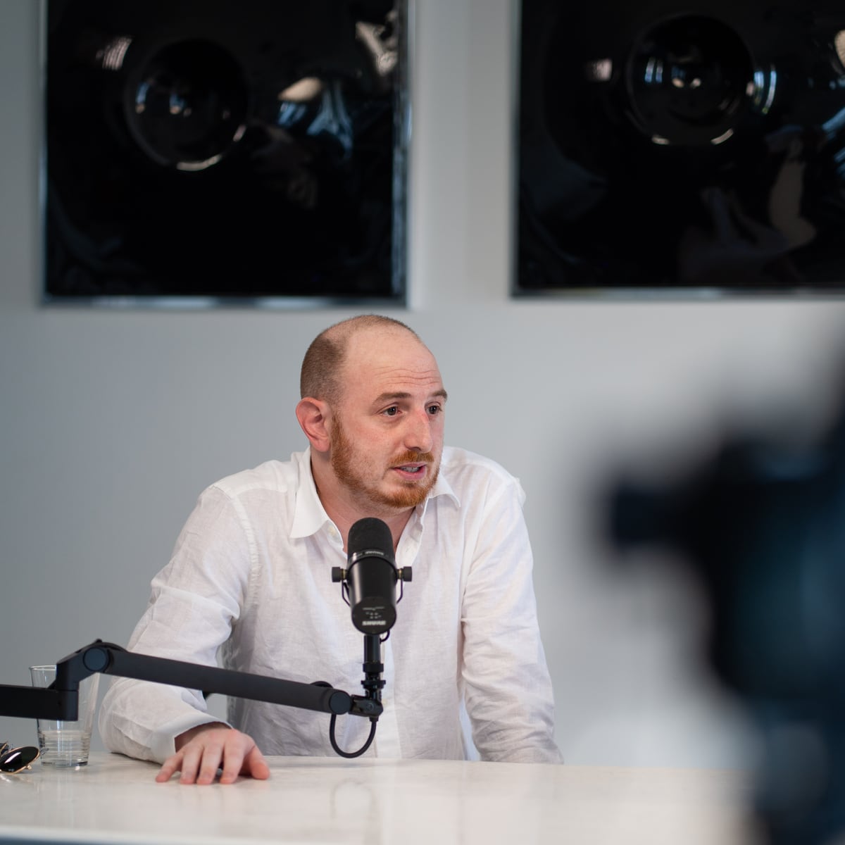 Noah Plaue of NewtonX in a white shirt talking at the microphone on the Conveo podcast set at Cannes Lions 2026
