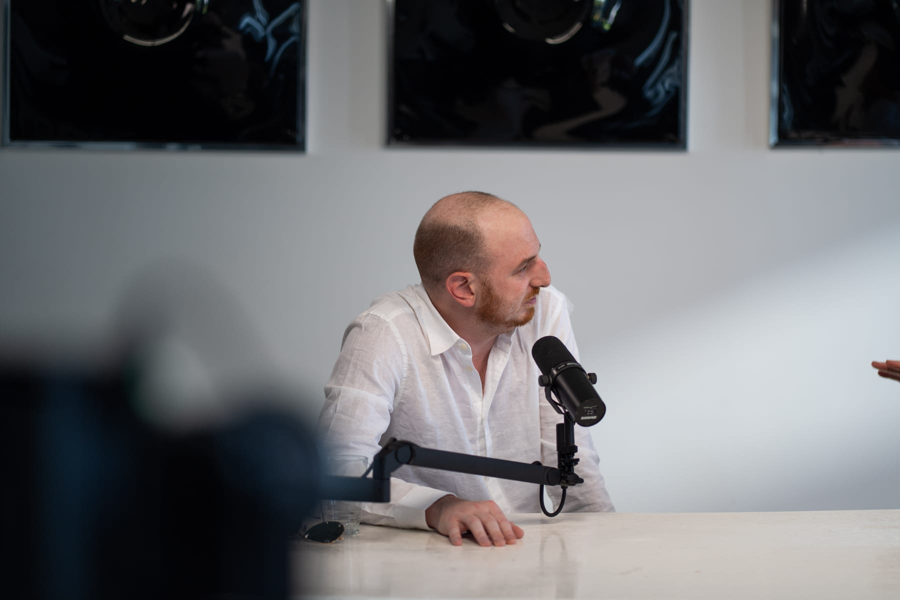 Noah Plaue in a white shirt speaking into a microphone, with a blurred camera in the foreground, at Cannes Lions 2026