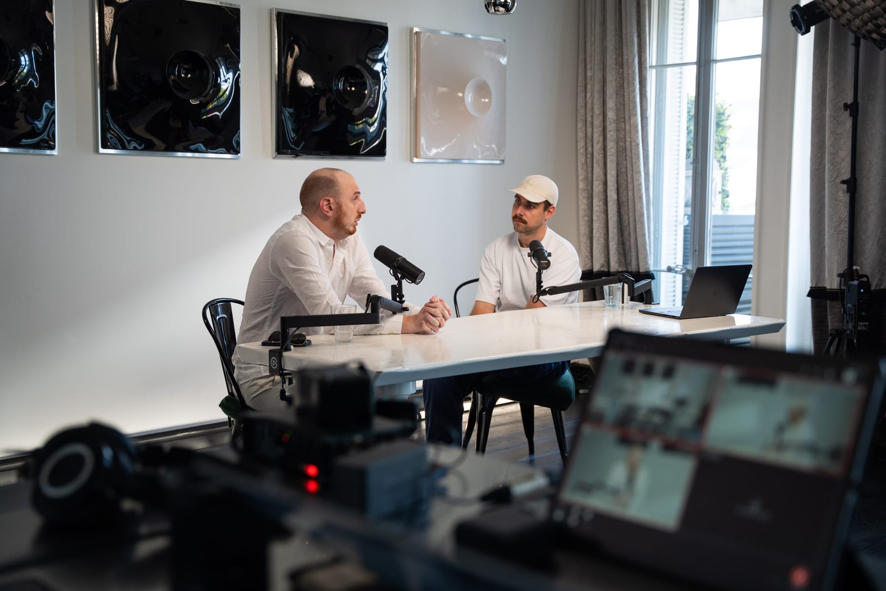 Laptop monitors in the foreground show the live feed as Noah Plaue and the host record at the table at Cannes Lions 2026