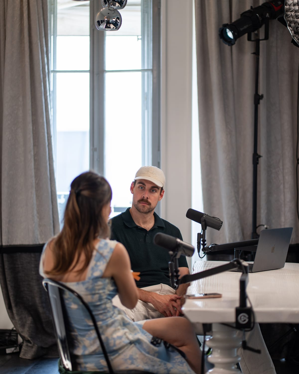 Over-the-shoulder view of Özge Akcizmeci talking with the host, who looks back at her from across the table at Cannes Lions 2026