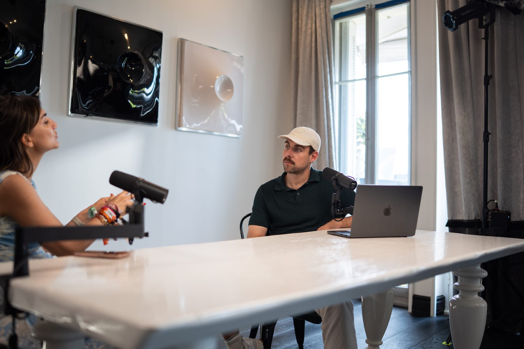 Özge Akcizmeci explains a point with her hands while the host looks on from behind his laptop at Cannes Lions 2026