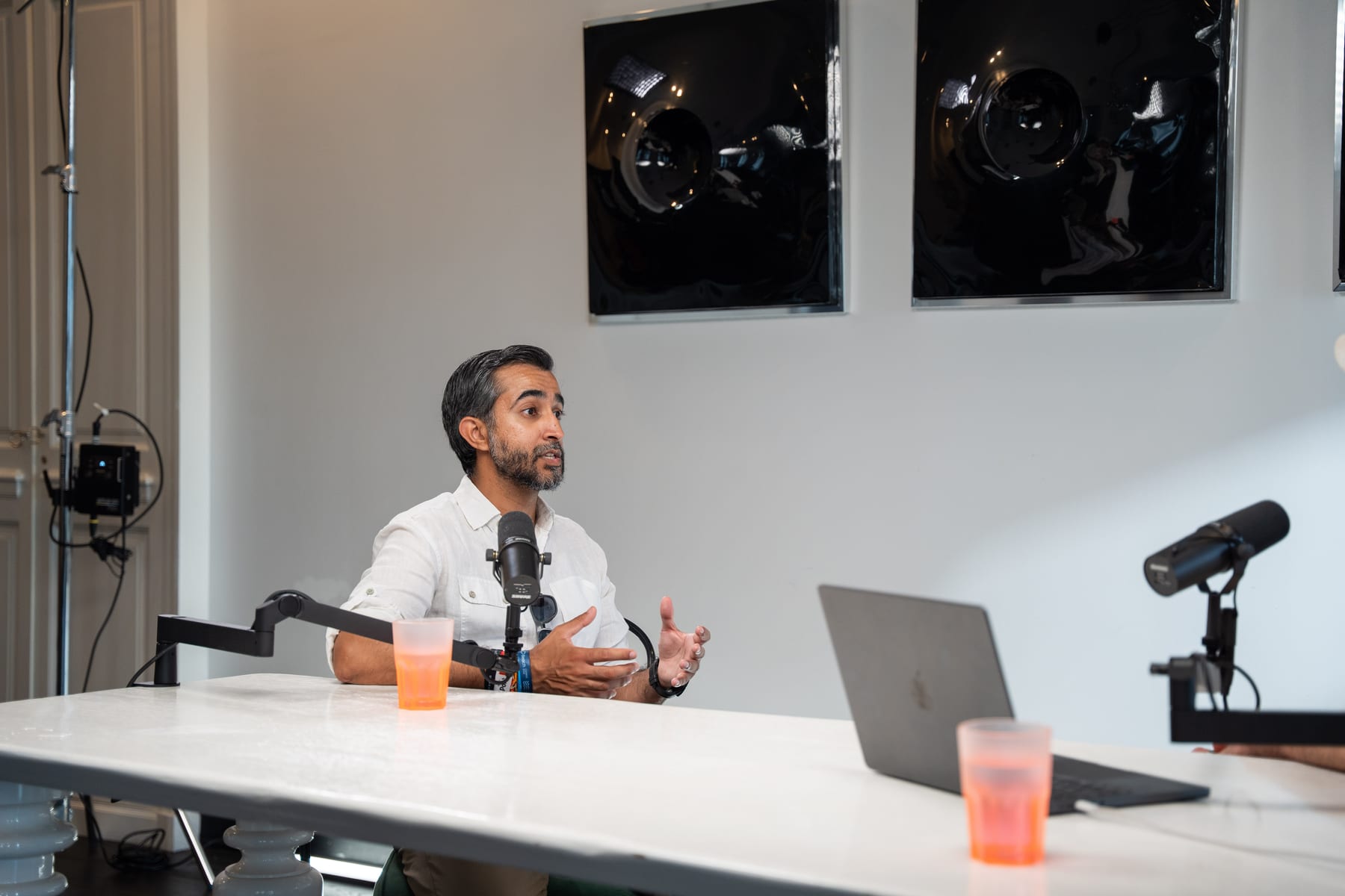 Ravi Rabheru gesturing with both hands as he speaks into a microphone at the Conveo podcast table at Cannes Lions 2026