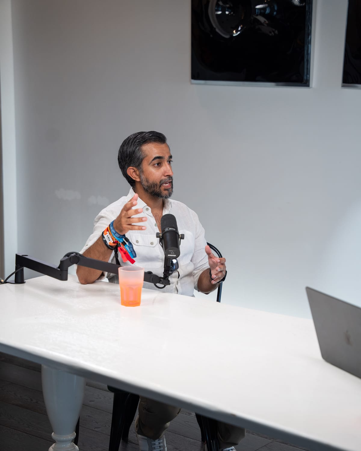 Ravi Rabheru seated at the end of a long white table, explaining a point with open hands on the Conveo podcast set at Cannes Lions 2026