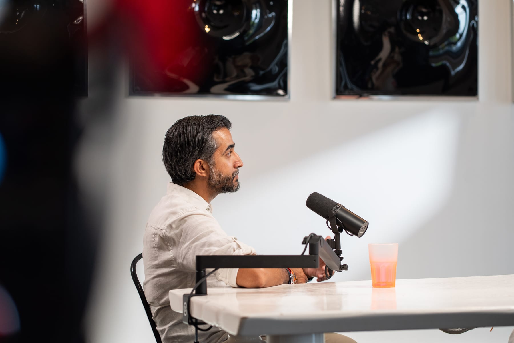 Profile of Ravi Rabheru at the microphone, looking across the table toward the host on the Conveo podcast set at Cannes Lions 2026