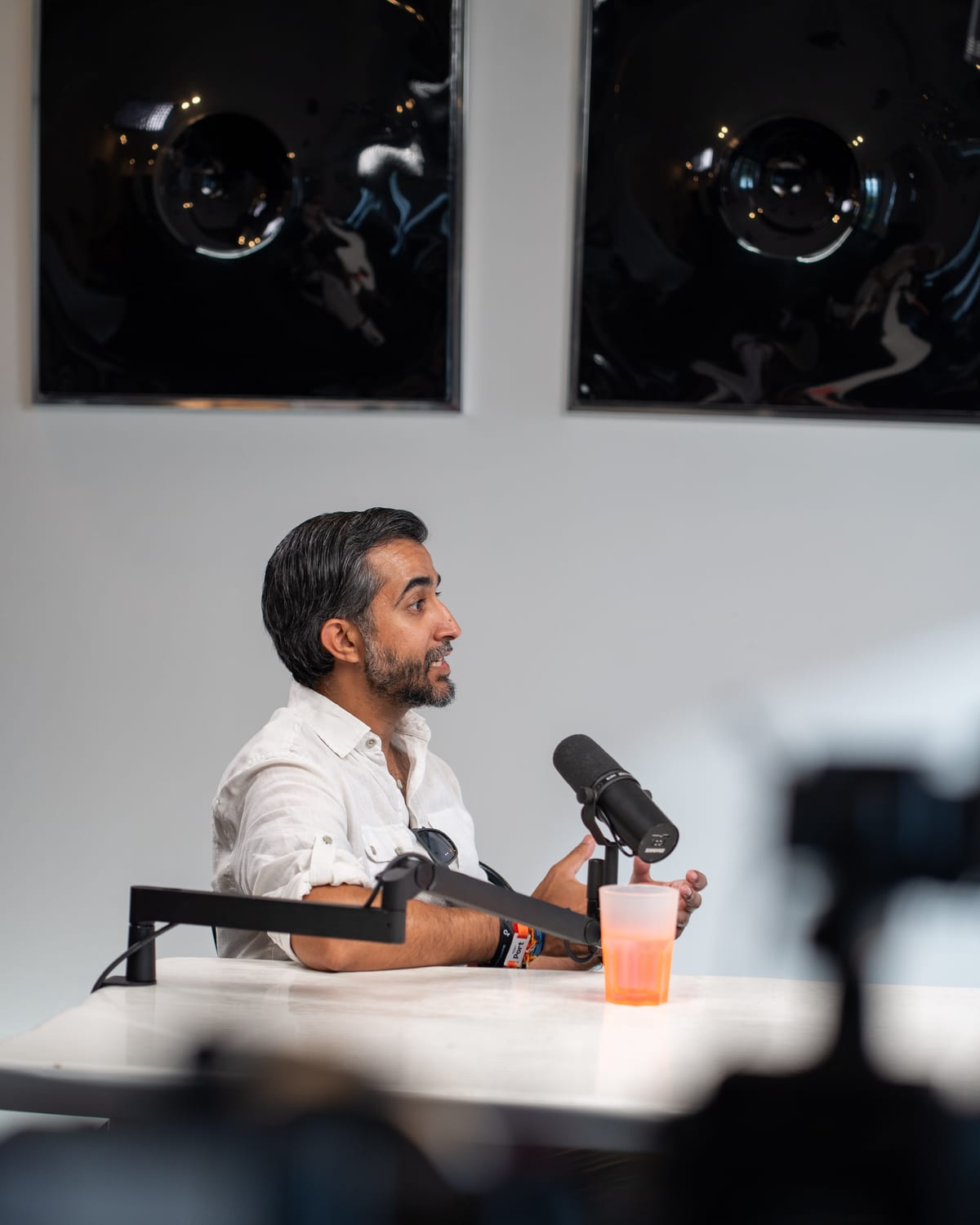Ravi Rabheru in profile mid-sentence at the microphone, with a blurred camera in the foreground, at Cannes Lions 2026