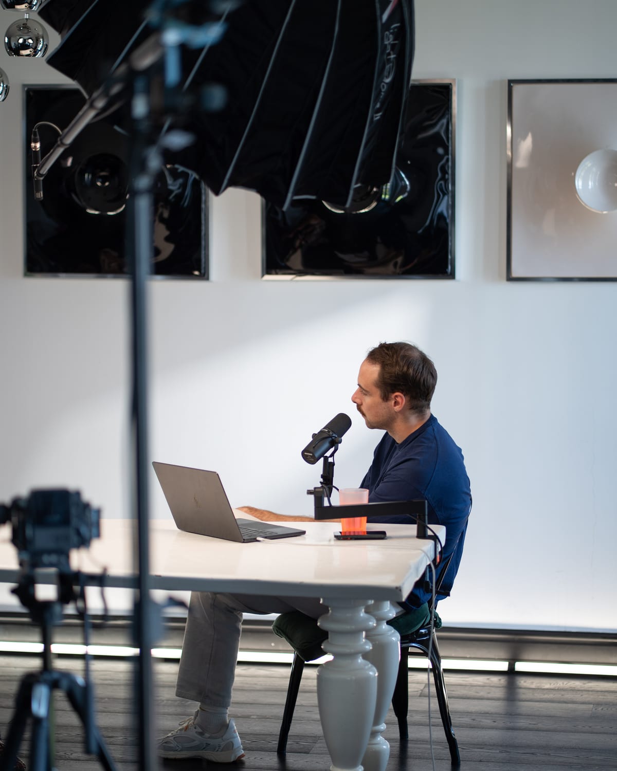 Conveo host Tom Husson at his laptop and microphone, framed by studio lights and a camera at Cannes Lions 2026